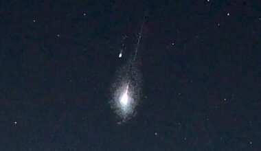 Two meteors are pictured streaking Earthward through a black sky peppered with white stars.
