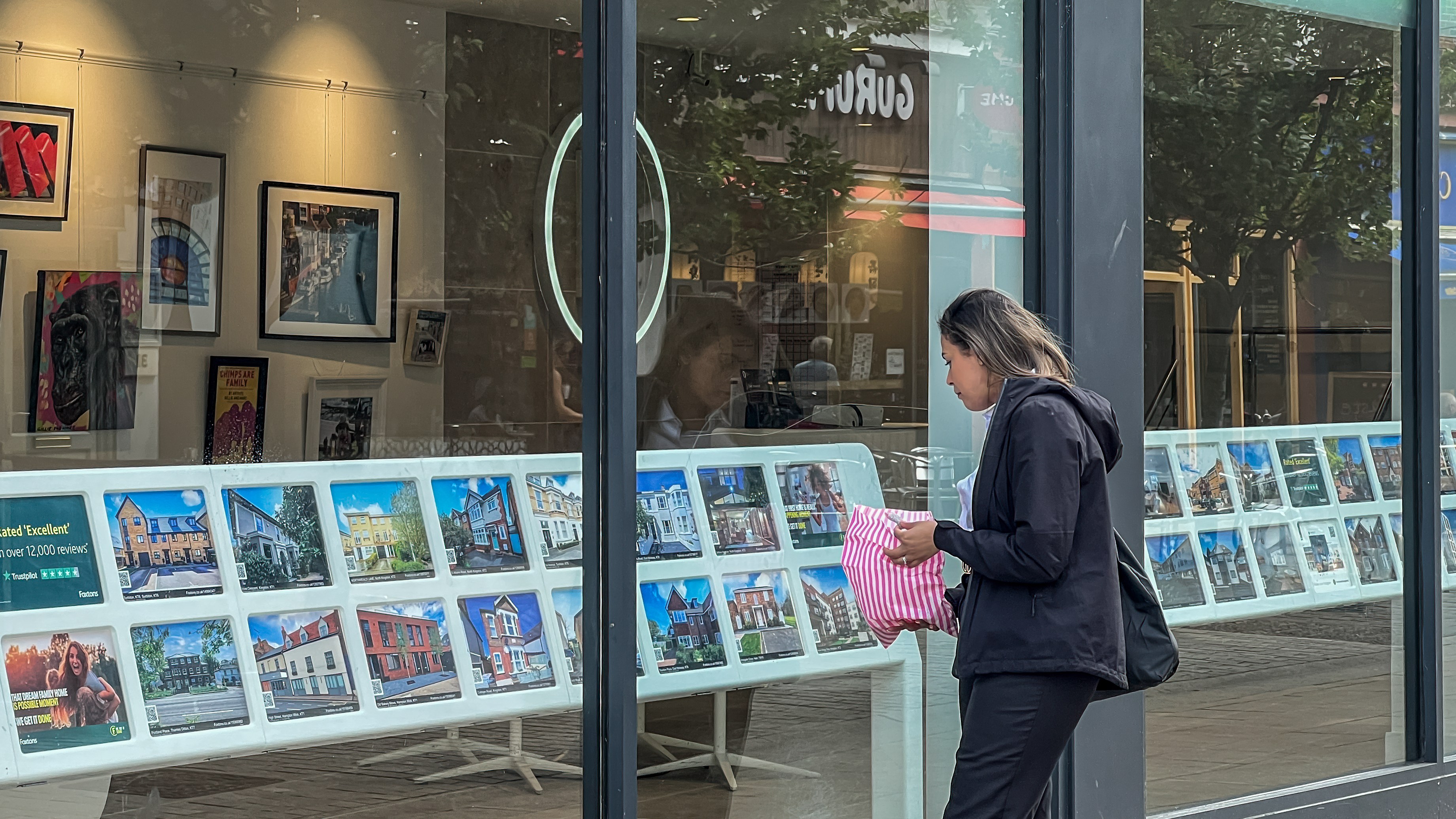 A young woman viewing properties in an estate agent's window.