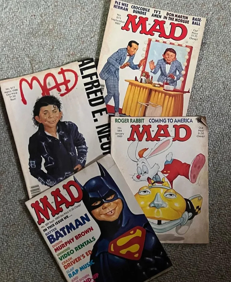 Four vintage Mad magazine covers are displayed. Each features different humorous illustrations and parodies of pop culture from the past decades