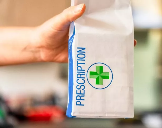 Close-up of a paper prescription bag, held out by a pharmacist