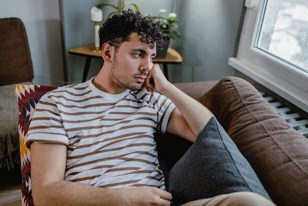 Man laying on sofa, looking sad