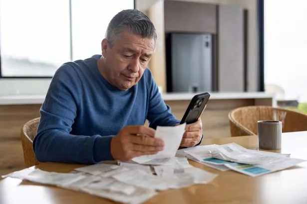 Portrait of a retired Latin American man at home paying bills online and looking worried - home finances concepts