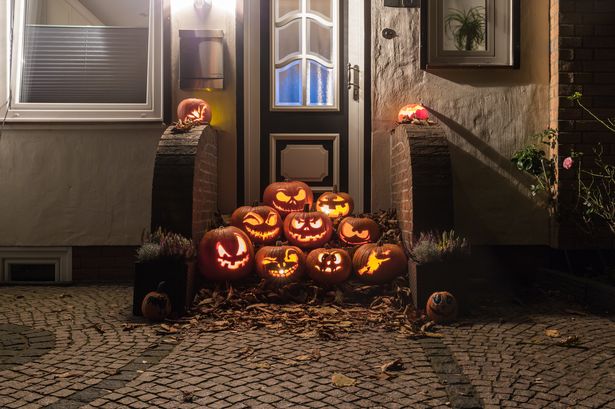 Night shot of illuminated pumpkins in front of a house