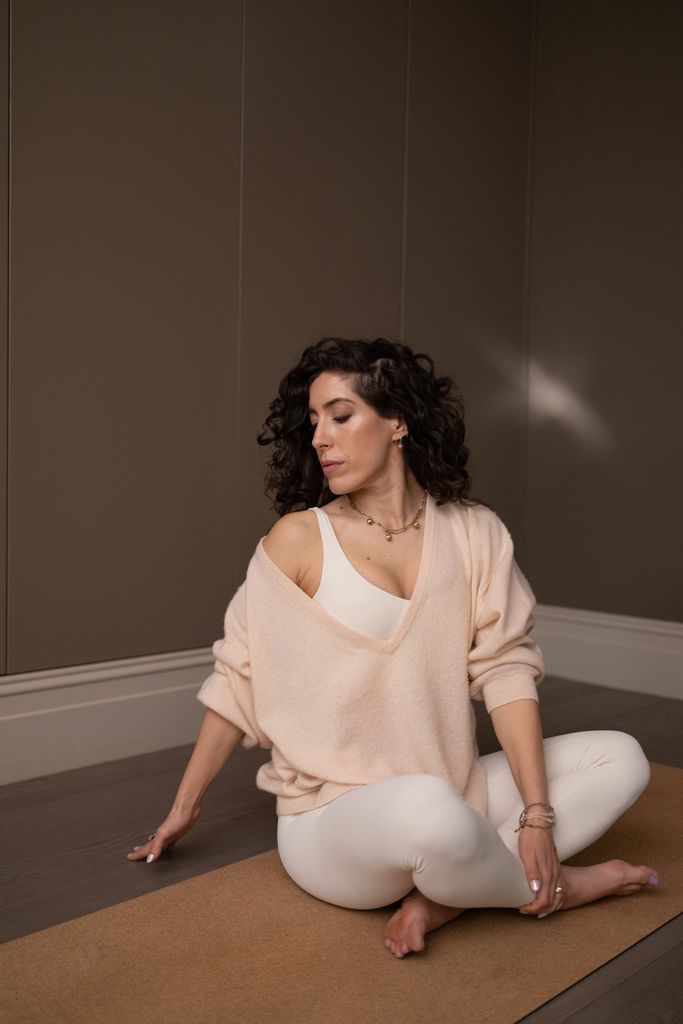 woman in light activewear sitting on a yoga mat stretching 