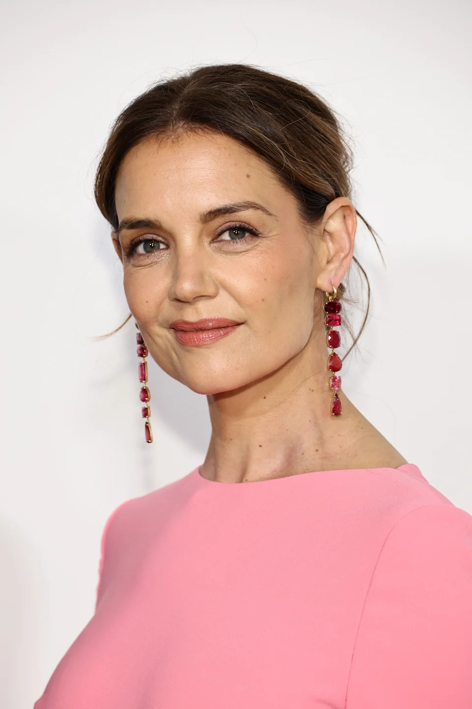 Person wearing a simple, elegant dress and long earrings, posing for a photo