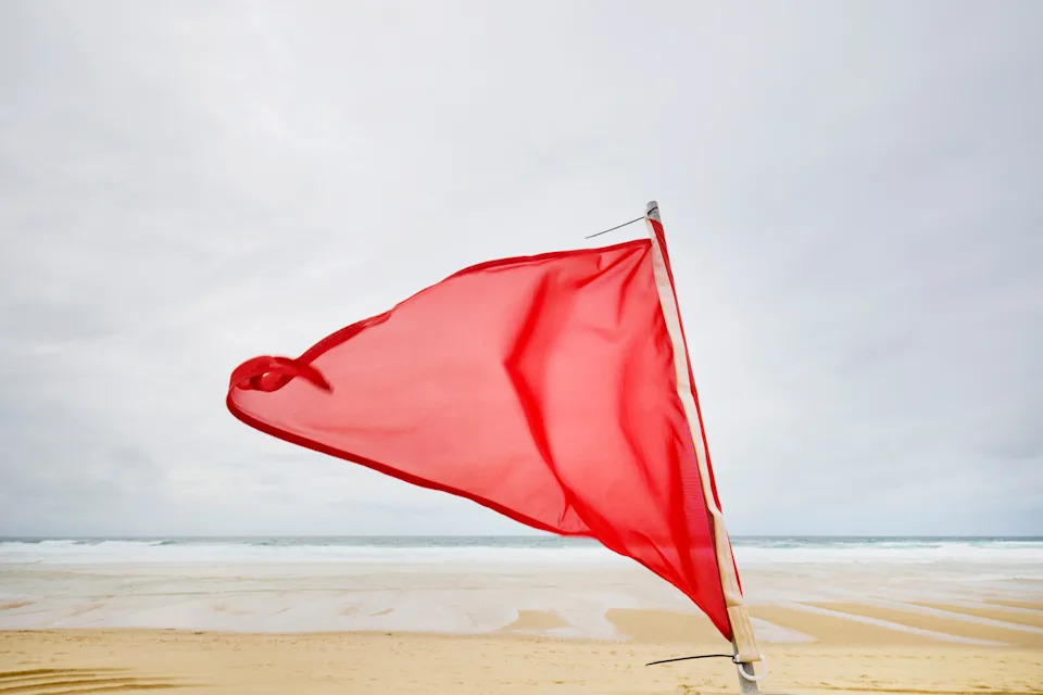 Red flag waving on a beach, signaling potential danger or caution for swimmers