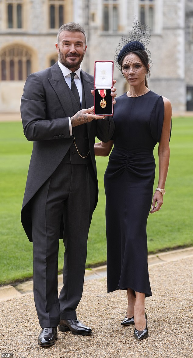David and wife Victoria pose with his medal after he received his honour at Windsor Castle