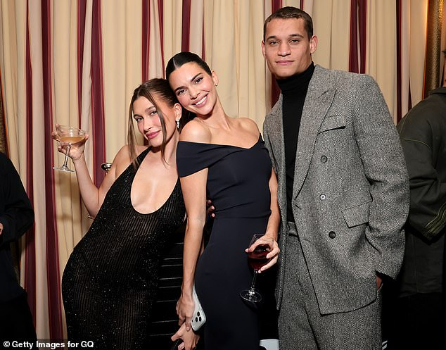 Bieber held a champagne glass while leaning on Kendall Jenner who held a glass of red wine; seen with actor Tyriq Withers