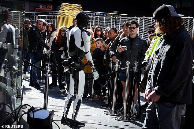 A crowd watches and interacts with a Tesla Optimus robot outside the Nasdaq Market site in New York City in October