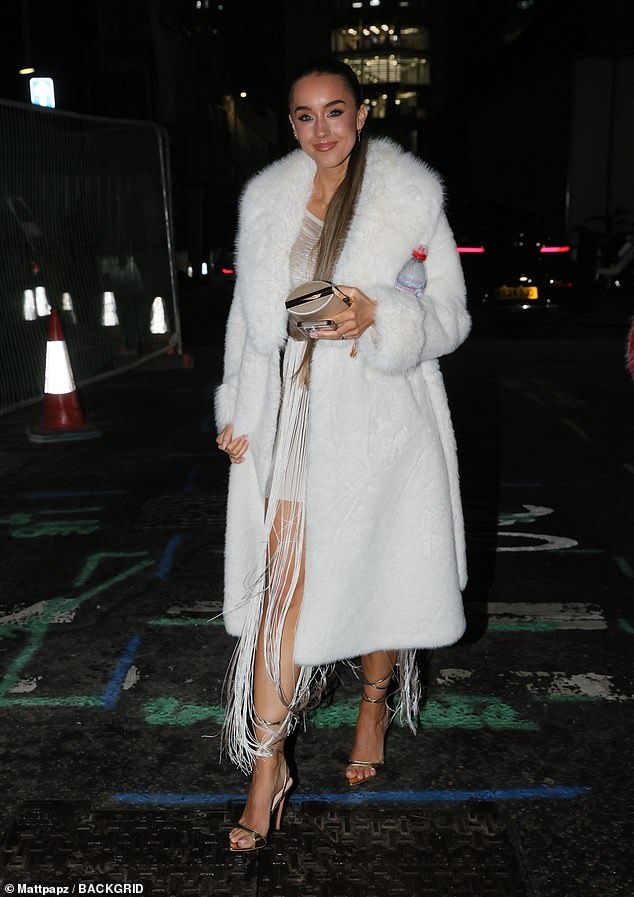 Emily kept warm in a long white fur coat as she exited carrying a bottle of water