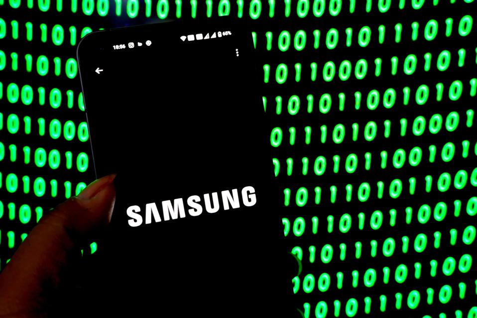 Samsung Logo seen displayed on a smartphone with green binary code in background.