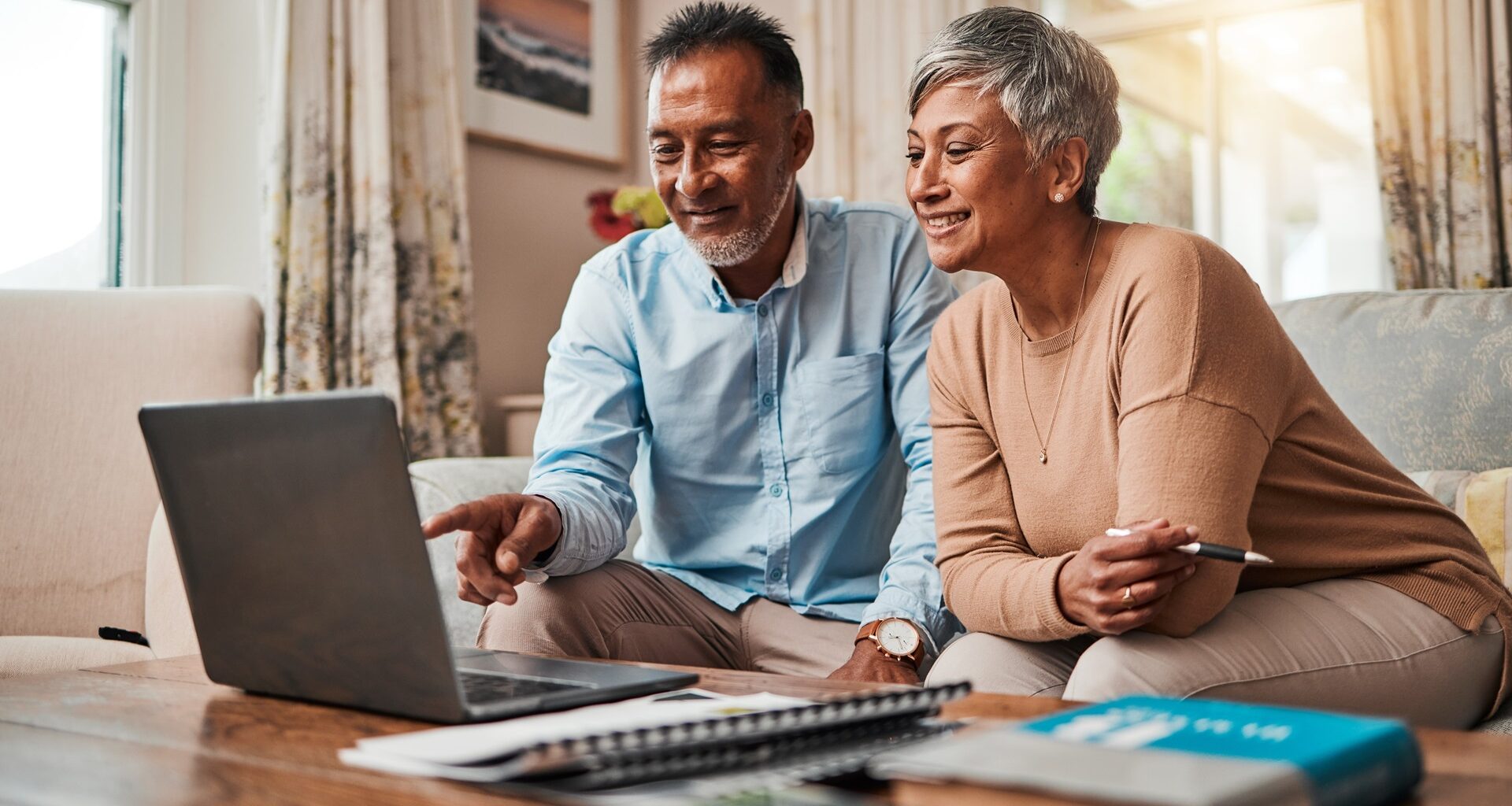 Picture of a mature couple on sofa using a laptop for planning finances, retirement, budget and more.