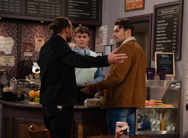 Lewis watches Kev and Mack in a tense exchange in Emmerdale
