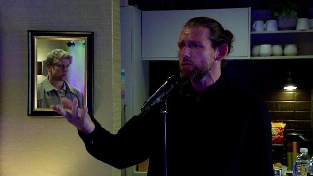 Kev standing by a microphone in Emmerdale