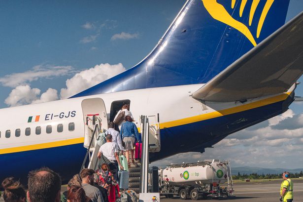 People walk to board a Ryanair plane heading to Porto in Portugal on the runway of Carcassonne airport in Aude, France on May 21, 2024. (Photo by Idriss Bigou-Gilles / Hans Lucas / Hans Lucas via AFP) (Photo by IDRISS BIGOU-GILLES/Hans Lucas/AFP via Getty Images)