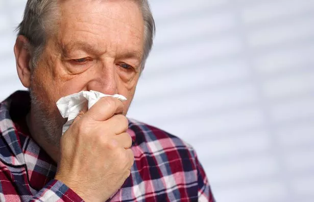 Senior man with a cold blowing his nose