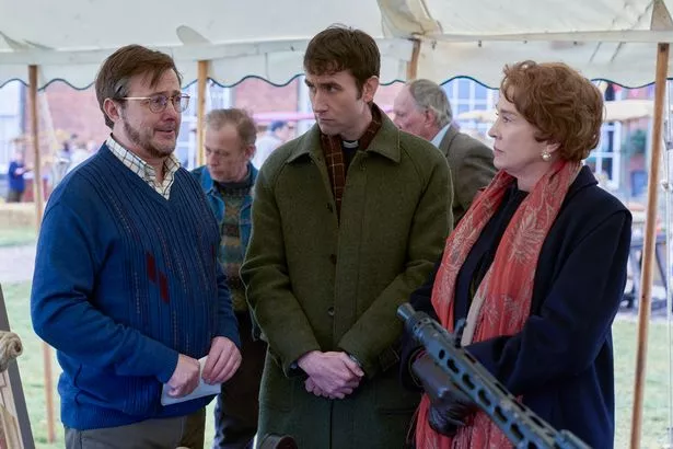 A man and a woman having a conversation with a man with glasses