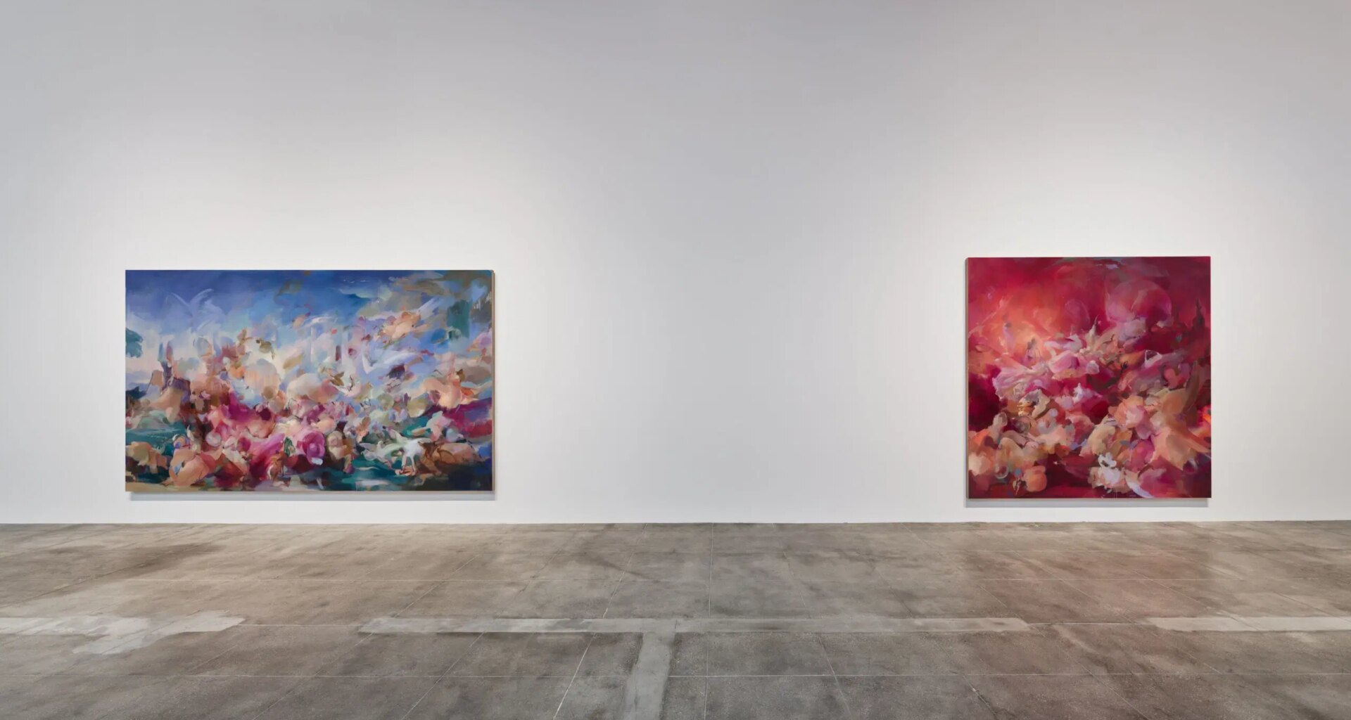 Two abstract paintings with vibrant colors displayed on a gallery wall over a polished concrete floor.