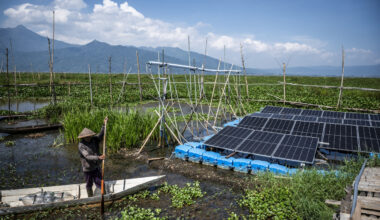 A farmer stands on a boat passing through solar panels on Oct. 12, installed as part of the Rawa Pening floating solar photovoltaic plant in Tuntang, Semarang regency, Central Java.
