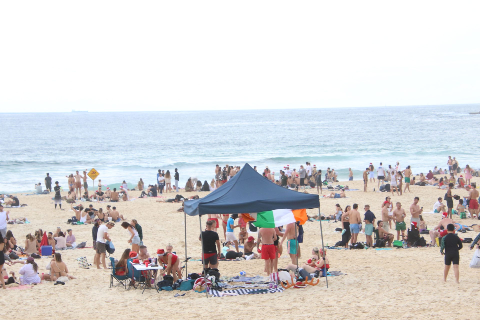 2W982DD Sydney, Australia. 25th December 2023. Locals and backpackers spent Christmas Day at Bondi Beach some wearing Santa hats. The weather was fine and 23 degrees Celsius on Christmas Day at Bondi Beach with some light rain in the evening. Credit: Richard Milnes/Alamy Live News