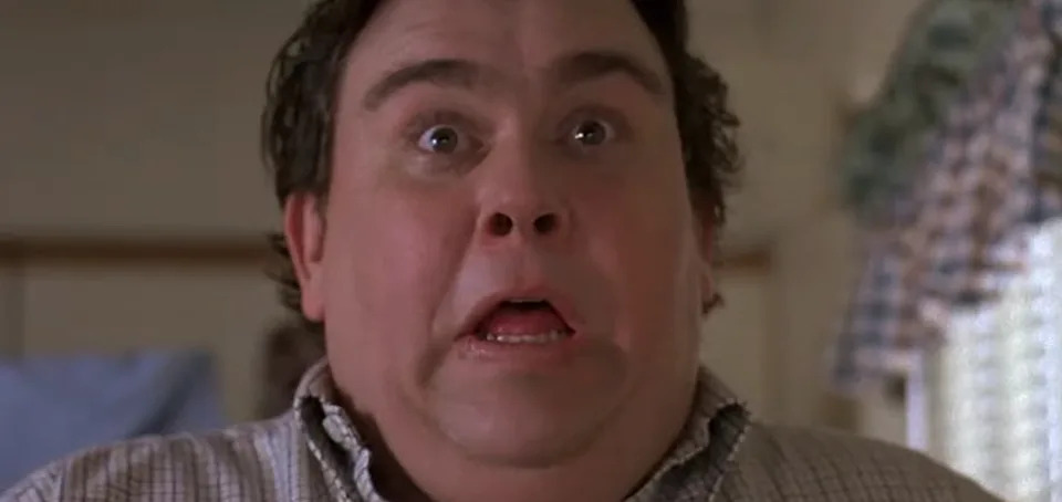 A surprised man with an open mouth and wide eyes, standing indoors