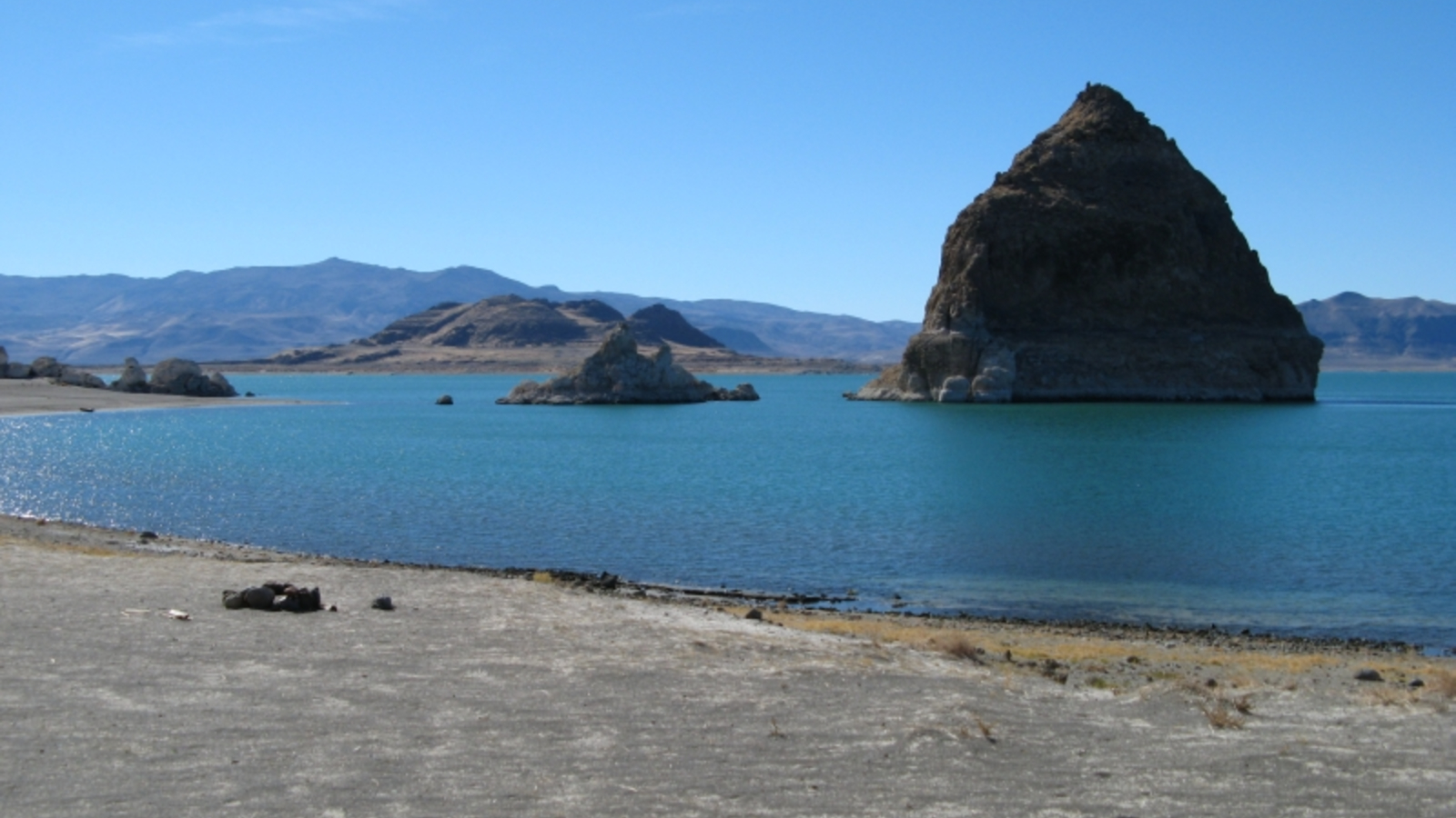 A photo of Pyramid Lake taken from the shoreline showing a large pyramid-like tufa on a nearby island