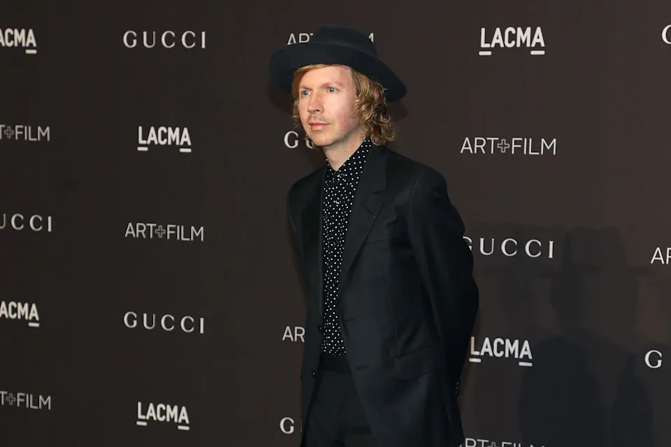 Person in a polka dot shirt, suit, and wide-brim hat on the red carpet at a LACMA event backdrop