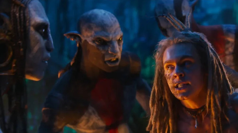 Sam Champion as Spider being held hostage by Oona Chaplin as Varang in the middle of a jungle in Avatar: Fire and Ash