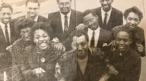Birmingham Evening Mail A newspaper cutting shows the singer with choir members in a black and white photo, The singer is stood in the middle with choristers standing around him holding his arms and smiling. 