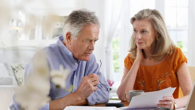 Mature couple with bills sitting at dining table in house
