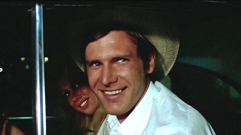 Harrison Ford's Bob Falfa smiles as he sits in a car in American Graffiti