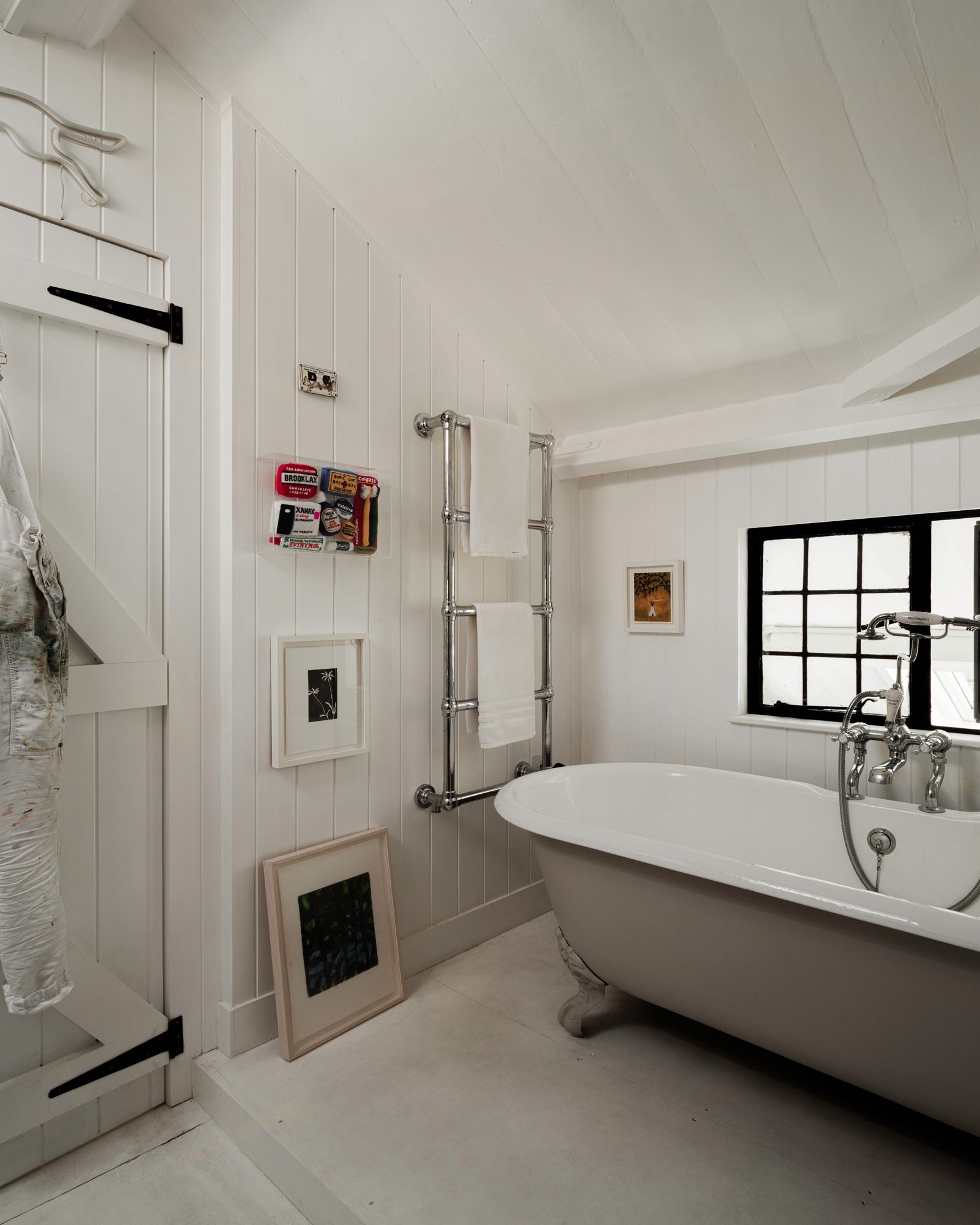 A piece by Lucy Sparrow hangs on the wall in the bathroom. An internal window looks out over the studio below.