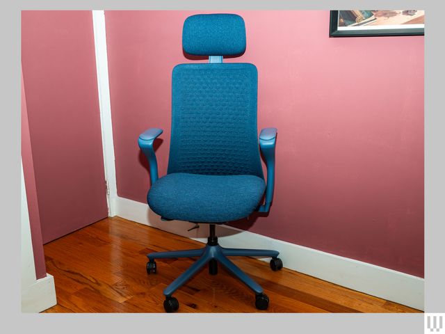 Front view of blue office chair in a room soft pink walls and hardwood floors