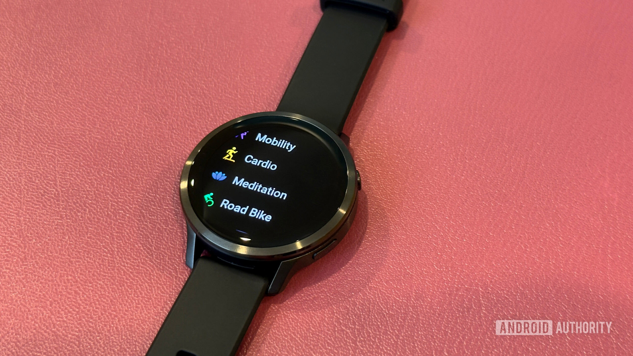 A Garmin Venu 4 rests on a leather surface and displays workout types.