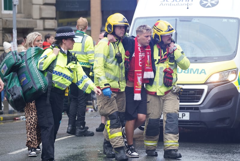 A Liverpool fan being helped from the scene by emergency personnel. Photograph: Owen Humphreys/PA Wire 