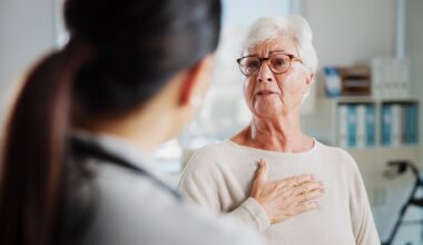 Elderly lady holding chest in pain whilst talking to a healthcare worker
