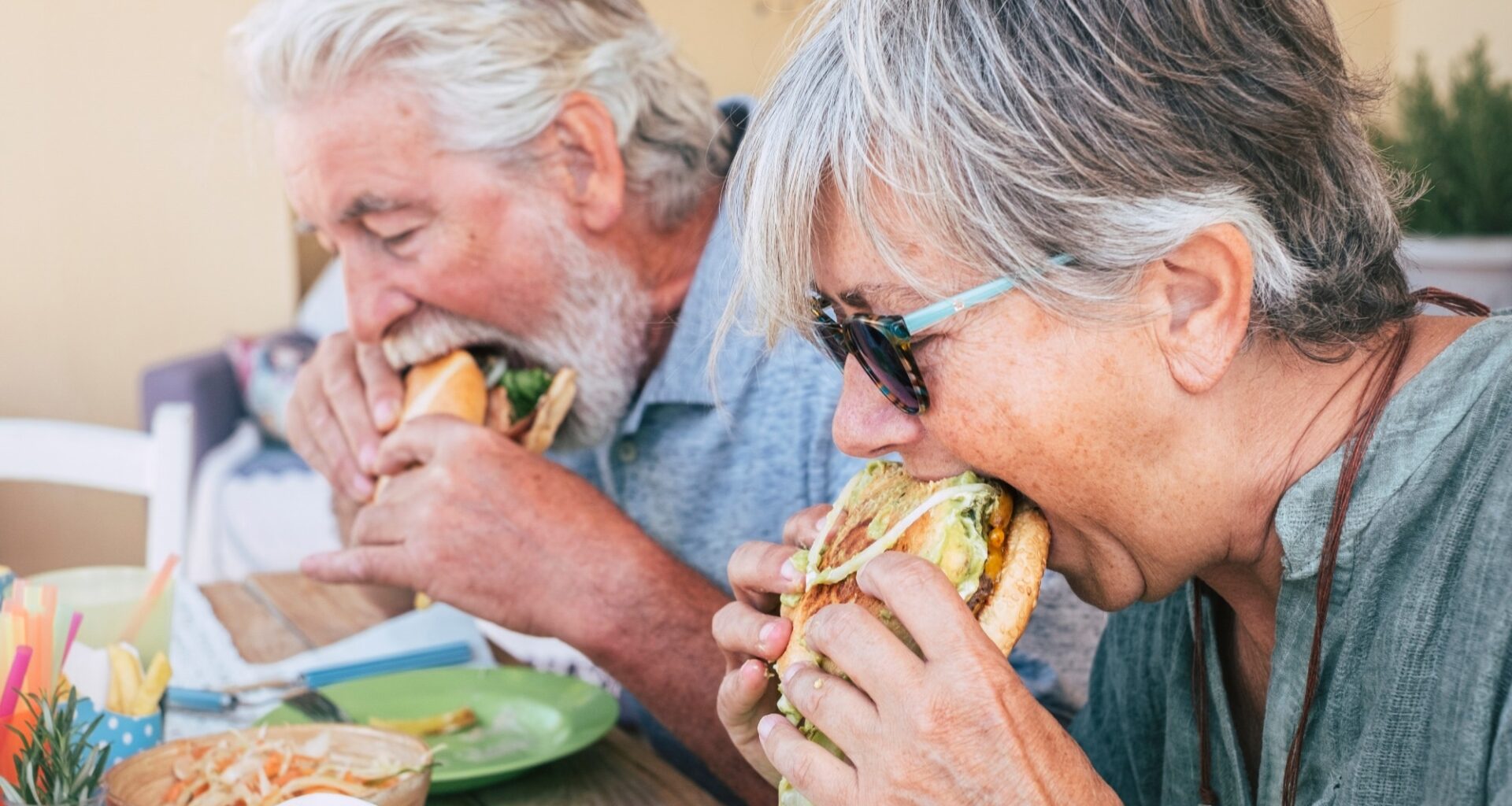 Couple of senior man and woman eating burgers