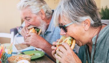 Couple of senior man and woman eating burgers