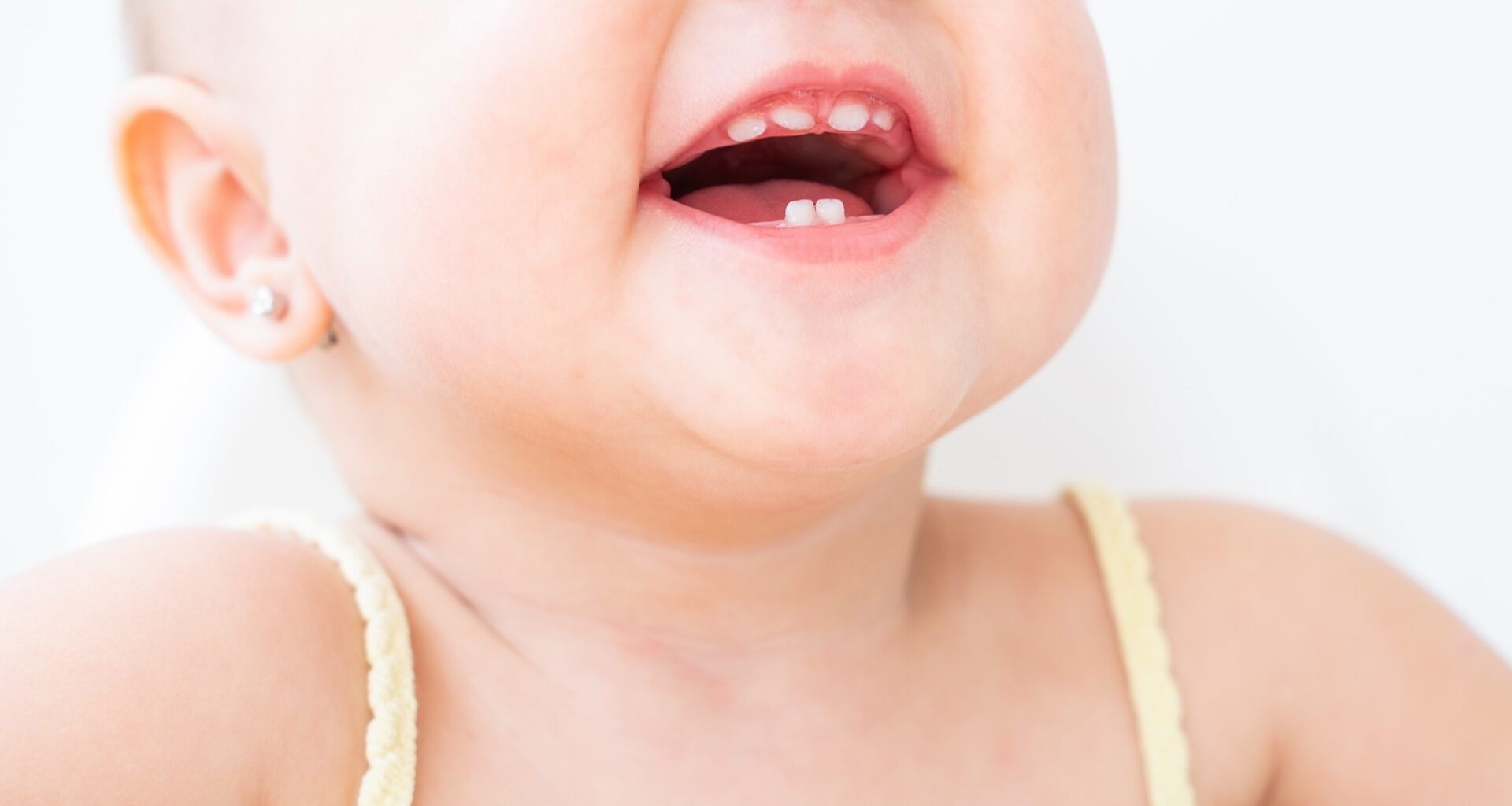 close up baby girl smiling with first teeth