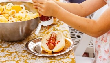 A little girl squeezing ketchup on a hotdog