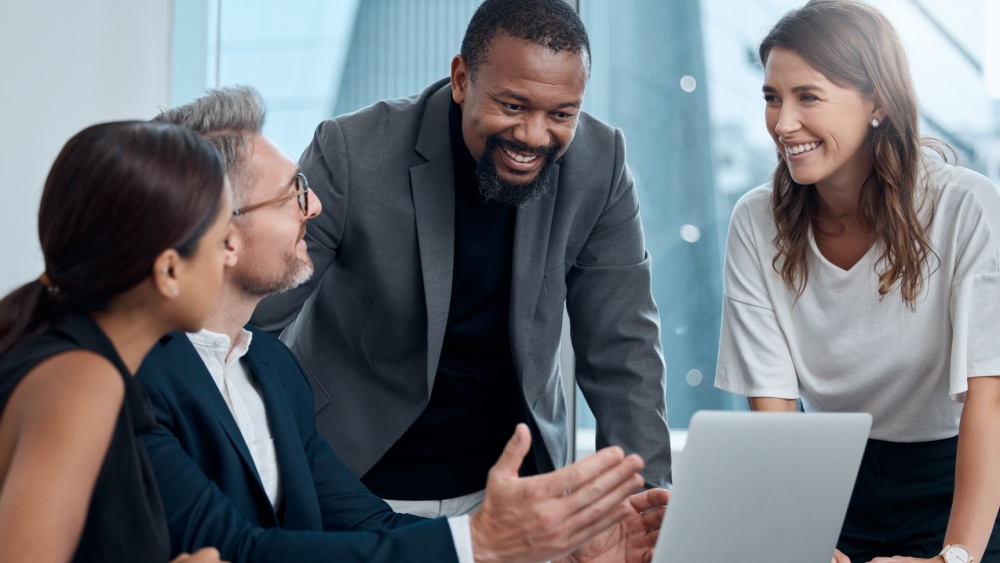 4 people in a corporate setting talking and laughing.