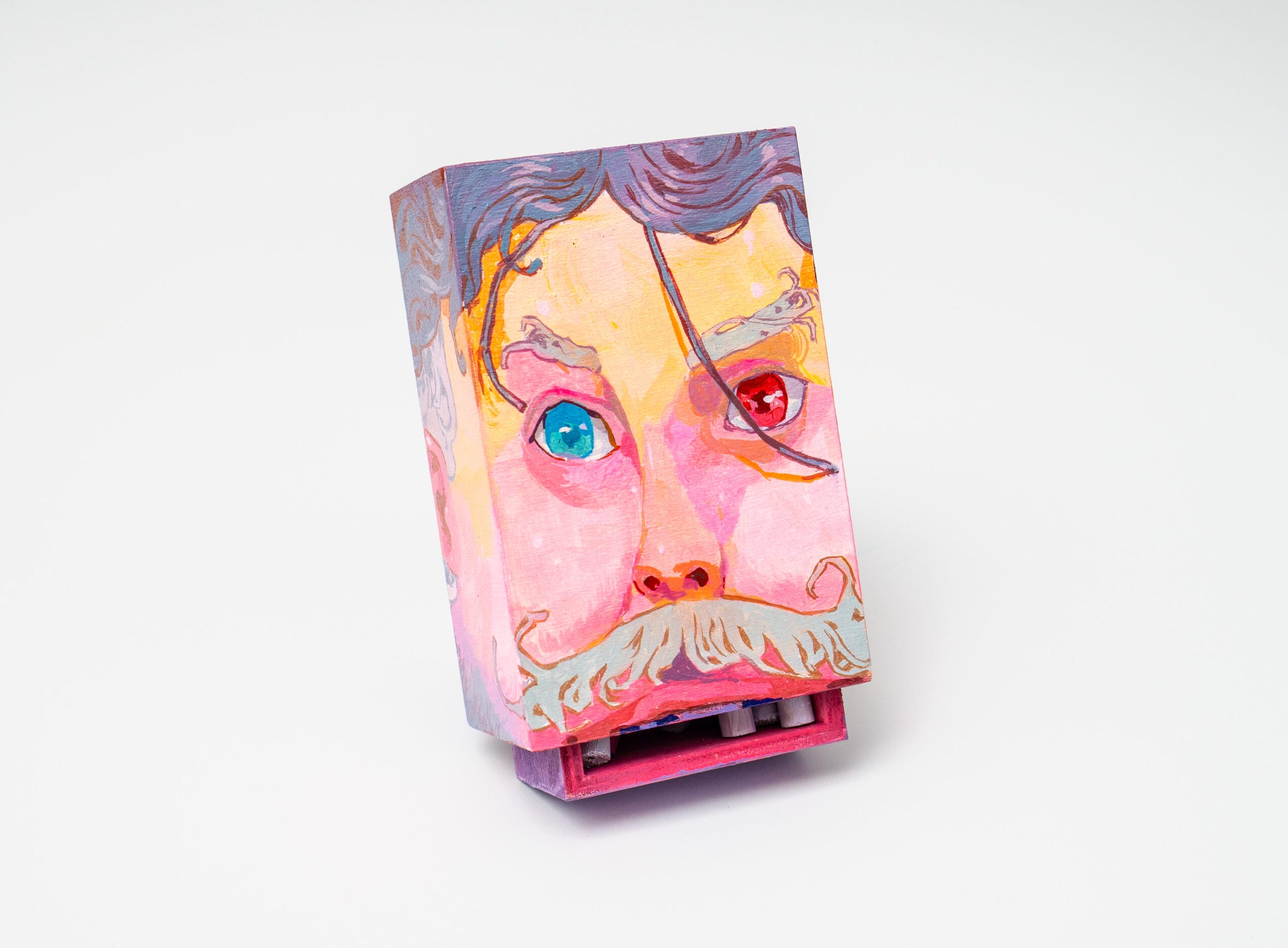a matchbox by Andrew Hem of a man's face in pink with a mustache