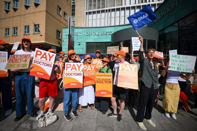 BRISTOL, ENGLAND - JULY 25: Striking doctors protest outside Bristol Royal Infirmary hospital on July 25, 2025 in Bristol, England. Resident doctors, formerly called junior doctors, have begun a five-day strike in England over a pay dispute with the government. Members of the British Medical Association (BMA) said earlier this week that they would go ahead with the strike, after talks with the government failed to reach an agreement over the doctors' demands for 'pay restoration.' Despite receiving an average 5.4% pay rise for this financial year and a 22% increase over the previous two years, the BMA says the resident doctors' earnings are still around 20% lower in real terms than in 2008. (Photo by Finnbarr Webster/Getty Images)