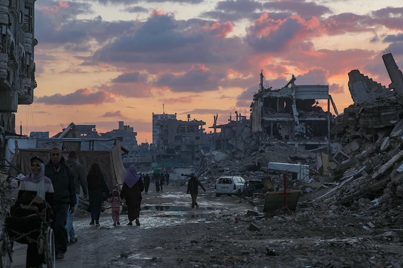Palestinians walk near destroyed buildings on a rainy day in the east of Gaza City on Sunday. Photograph: Mohammed Saber/EPA