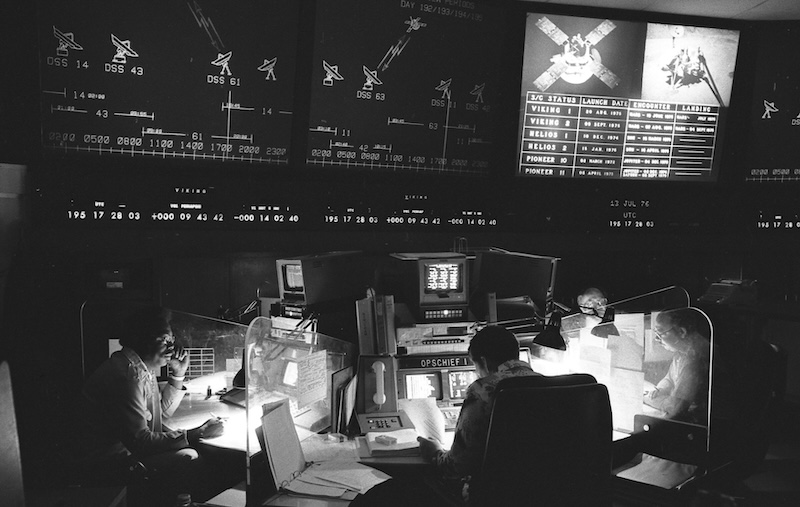 Black and white photo of a NASA control room with several people sitting at computer screens.
