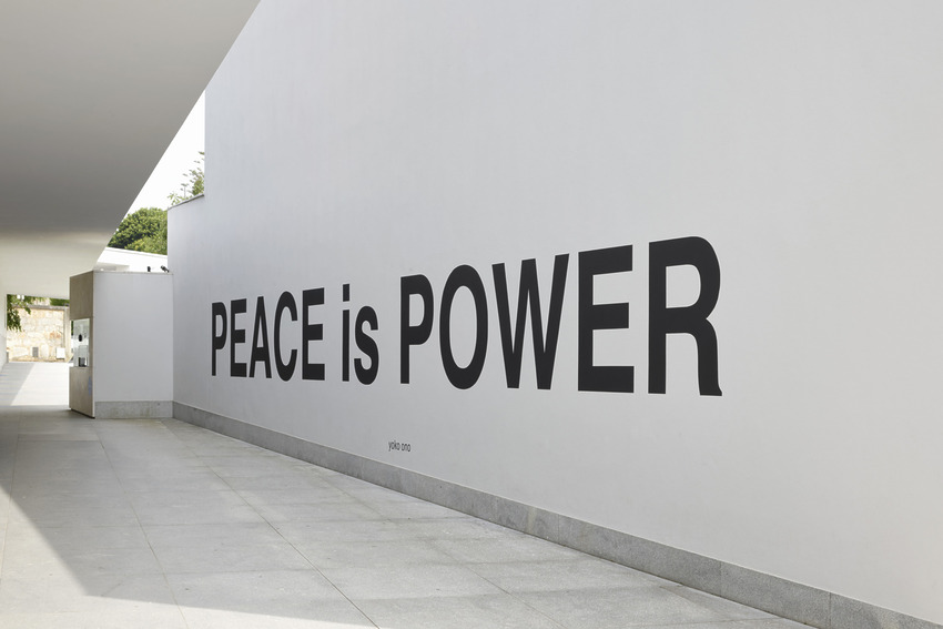 Wall with large black text reading "PEACE is POWER" in an outdoor modern minimalist setting.