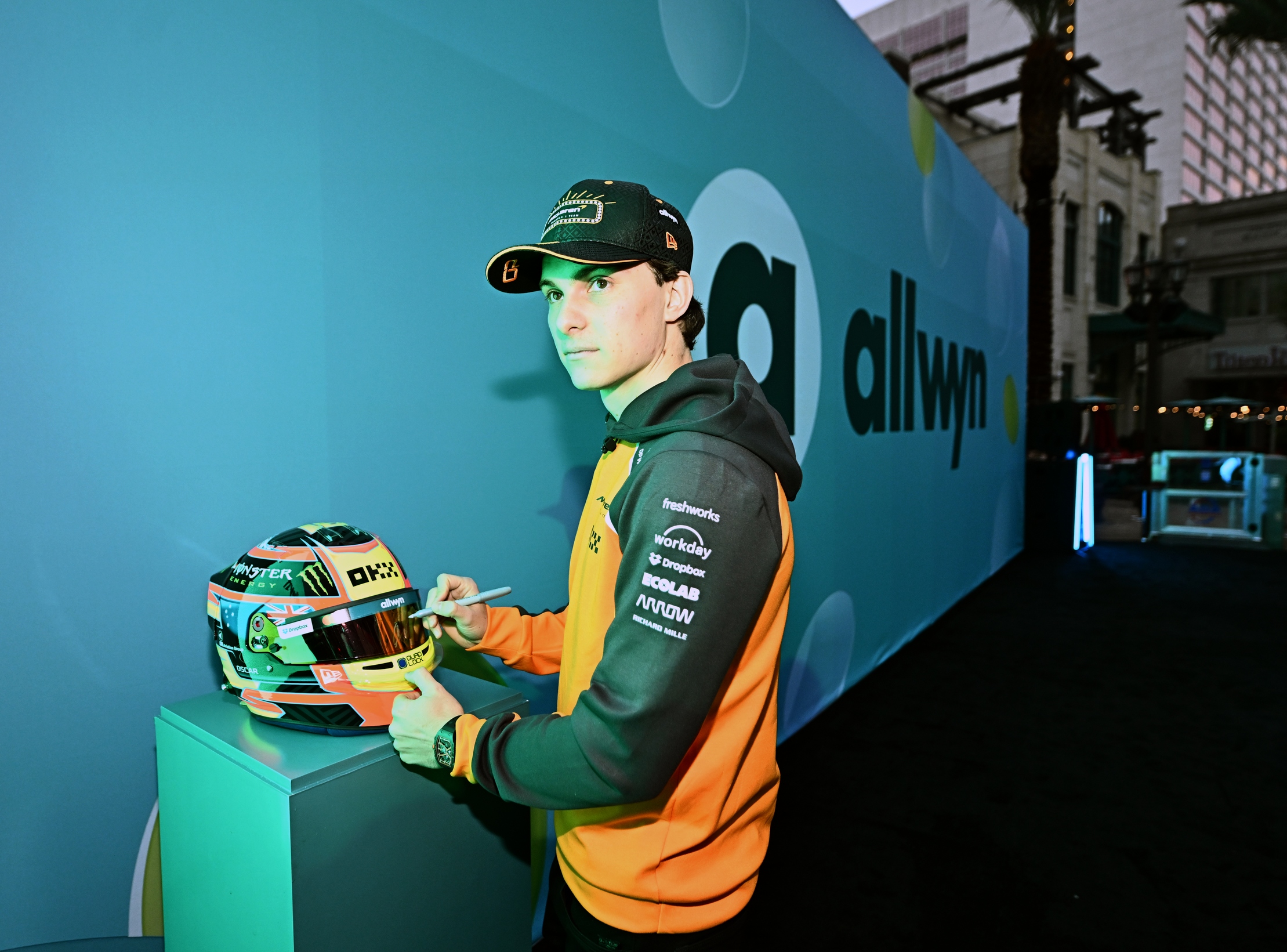 Oscar Piastri signs his helmet, one of the prizes that can be won from scratching a panel on the Scratch Car launched by Allwyn and the McLaren F1 Team