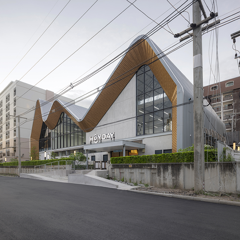 three asymmetrical curved gable roofs top ASWA’s community hub in thailand