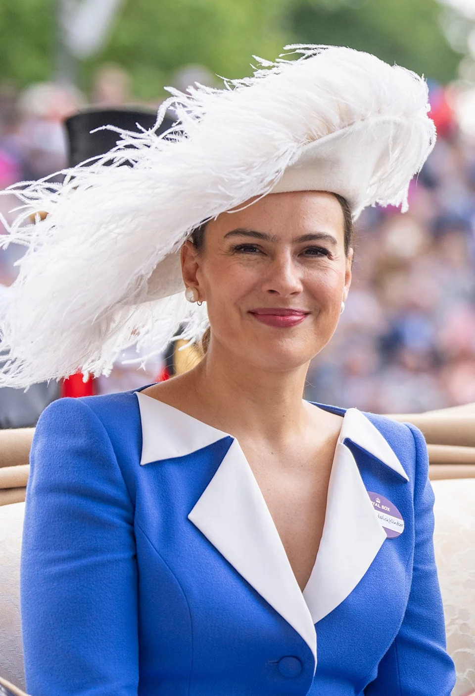 Sophie Winkleman wearing a blue and white dress with a matching white feather hat.