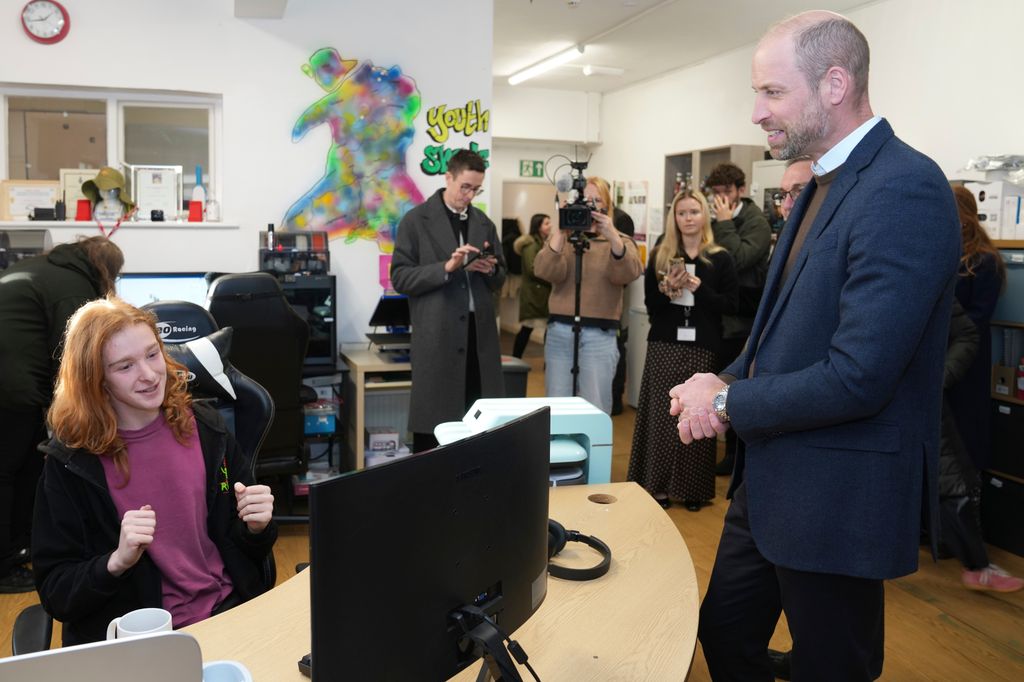 Prince William speaking to man behind desk